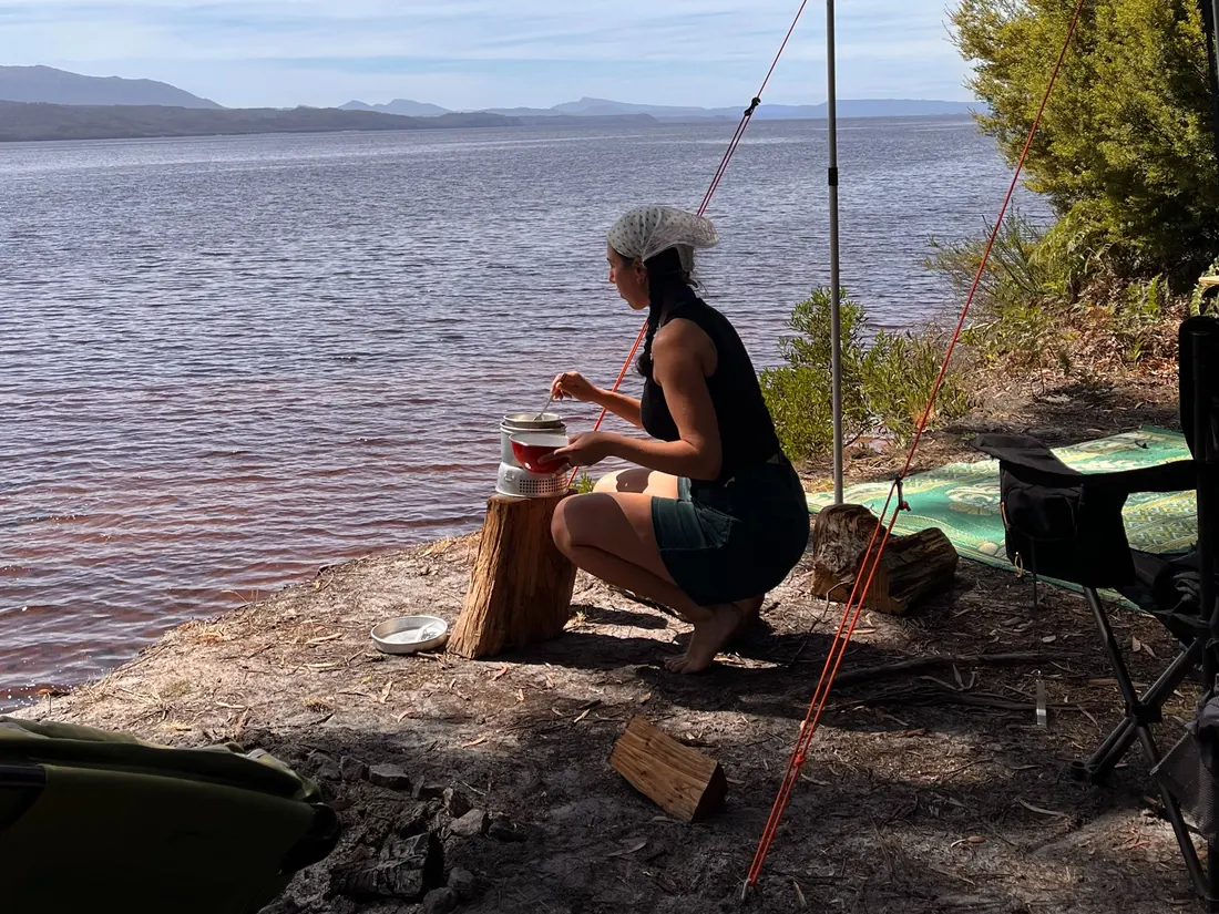 Liana cooking on a camp stove beside a still lake