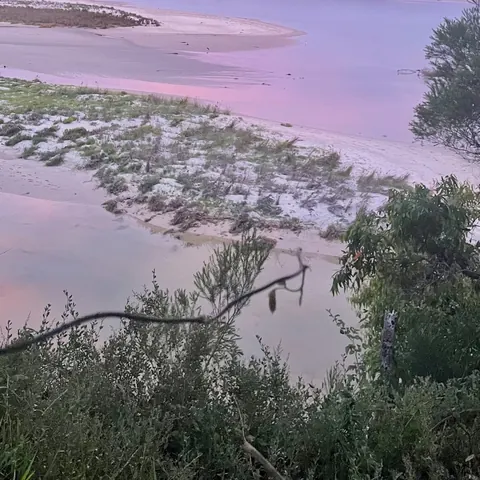 A lilac evening sky over a shallow, sandy bay